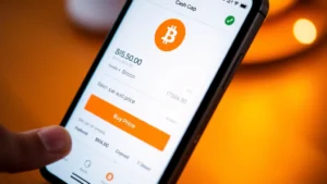 A smartphone displaying Cash App interface with Bitcoin purchase screen, showing price chart and buy button, warm lighting, modern fintech aesthetic, close-up detail of mobile app